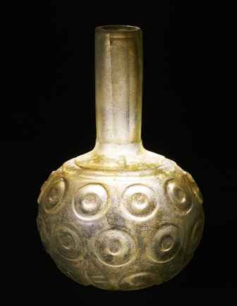Flaske af gulligt glas, med facet- og reliefslebet dekoration. 
